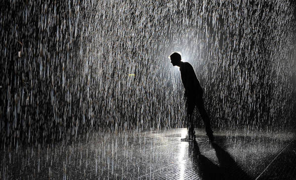 A man stands inside the new Rain Room at the Barbican center in London. The 'Rain Room' is a 100-square-meter room of falling water which visitors are invited to walk into, with sensors detecting where the visitors are standing.